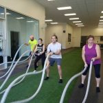 four people having fun with the workout ropes during a community workout at Synergy Gym