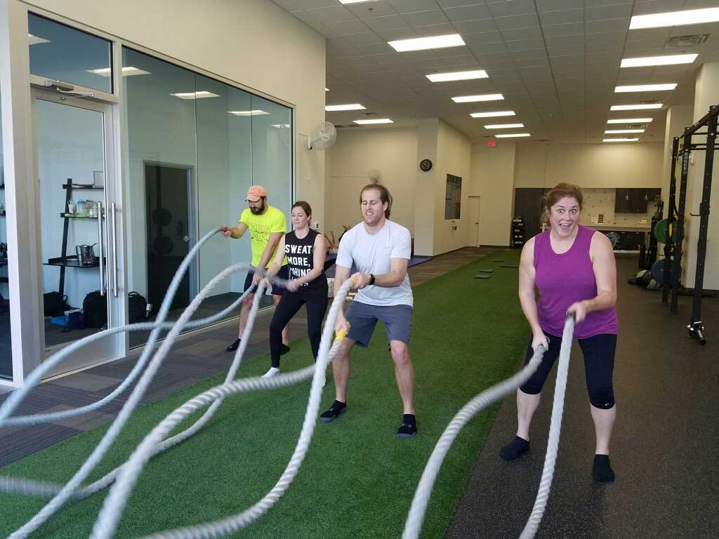 four people having fun with the workout ropes during a community workout at Synergy Gym